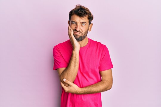 Handsome man with beard wearing casual pink tshirt over pink background thinking looking tired and bored with depression problems with crossed arms.