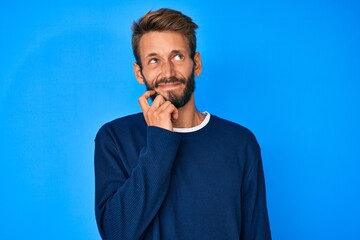 Handsome caucasian man with beard wearing casual sweater serious face thinking about question with hand on chin, thoughtful about confusing idea