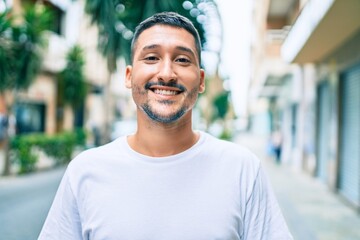 Young hispanic man smiling happy walking at street of city.