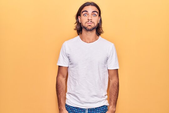 Young handsome man wearing casual clothes puffing cheeks with funny face. mouth inflated with air, crazy expression.