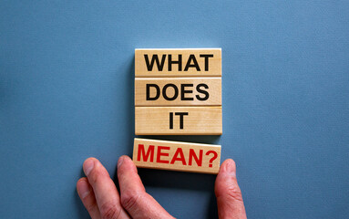 Male hand placing a block with word 'mean' on a blocks tower with words 'what does it mean'....