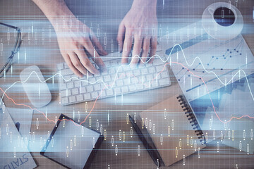 Multi exposure of man's hands typing over computer keyboard and forex graph hologram drawing. Top view. Financial markets concept.