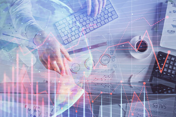 Multi exposure of man's hands typing over computer keyboard and forex graph hologram drawing. Top view. Financial markets concept.
