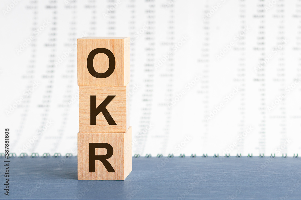 Aufkleber text okr on vertical row of wooden blocks on the background of columns of numbers