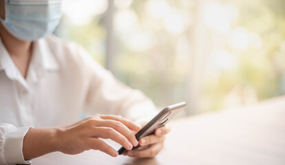 Female hand holding smartphone for find something on internet or shopping online while sitting one person for one table in the Co-working space