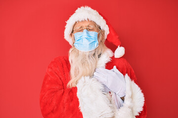 Old senior man wearing santa claus costume wearing safety mask smiling with hands on chest, eyes closed with grateful gesture on face. health concept.