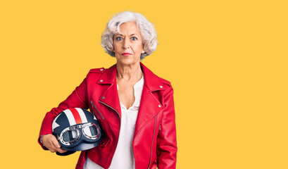 Senior grey-haired woman holding motorcycle helmet thinking attitude and sober expression looking self confident