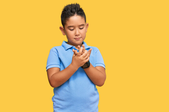 Little boy hispanic kid wearing casual clothes suffering pain on hands and fingers, arthritis inflammation