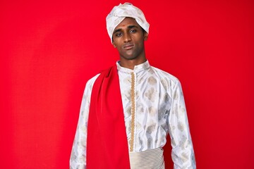 Handsome indian man wearing tradition sherwani saree clothes relaxed with serious expression on face. simple and natural looking at the camera.