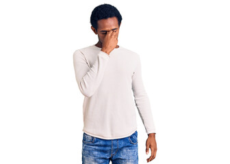 African handsome man wearing casual winter sweater tired rubbing nose and eyes feeling fatigue and...