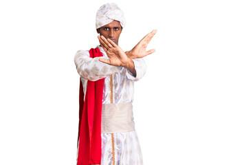African handsome man wearing tradition sherwani saree clothes rejection expression crossing arms and palms doing negative sign, angry face
