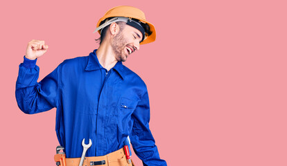 Young hispanic man wearing worker uniform dancing happy and cheerful, smiling moving casual and confident listening to music
