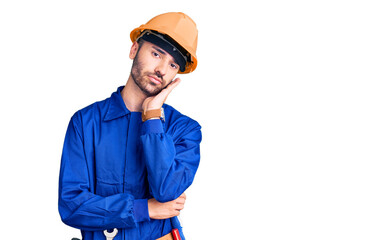 Young hispanic man wearing worker uniform thinking looking tired and bored with depression problems with crossed arms.