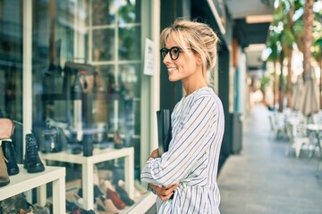 Fototapeta premium Young blonde businesswoman smiling happy looking showcase at the city.