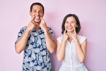 Beautiful couple wearing casual clothes smiling with open mouth, fingers pointing and forcing cheerful smile