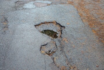 one big hole on the brown asphalt road