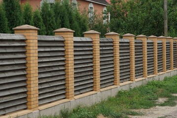 long brown fence wall made of wooden boards and bricks outdoors 