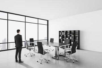 Businessman standing in conference interior with shelves with folders.
