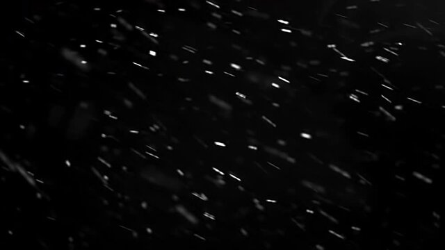 Real falling snow isolated on black background for composing, snowflakes bokeh falling during in snowstorm, snowing footage. Winter background. 4K video, winter, selective focus, blur