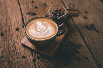 Latte art on hot latte coffee. Aroma coffee cup and coffee beans on wooden desk.