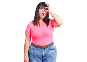 Young plus size woman wearing casual clothes doing ok gesture shocked with surprised face, eye looking through fingers. unbelieving expression.