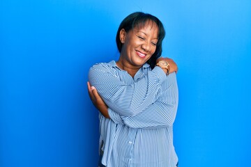 Middle age african american woman wearing casual clothes hugging oneself happy and positive,...