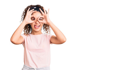 Fototapeta premium Beautiful kid girl with curly hair wearing casual clothes doing ok gesture like binoculars sticking tongue out, eyes looking through fingers. crazy expression.