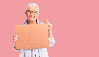 Senior beautiful woman with blue eyes and grey hair holding we need a change banner surprised with an idea or question pointing finger with happy face, number one