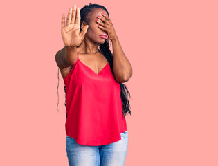 Obraz na płótnie Canvas Young african american woman wearing casual clothes covering eyes with hands and doing stop gesture with sad and fear expression. embarrassed and negative concept.
