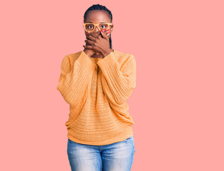 Young african american woman wearing casual clothes and glasses shocked covering mouth with hands...