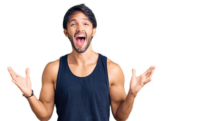 Handsome hispanic man wearing casual clothes celebrating mad and crazy for success with arms raised...