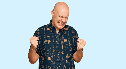 Naklejka premium Middle age bald man wearing casual clothes very happy and excited doing winner gesture with arms raised, smiling and screaming for success. celebration concept.