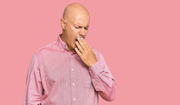 Middle age bald man wearing casual clothes bored yawning tired covering mouth with hand. restless and sleepiness.