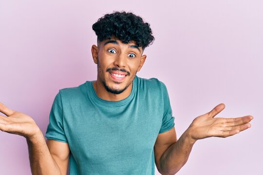 Young arab handsome man wearing casual clothes clueless and confused expression with arms and hands raised. doubt concept.