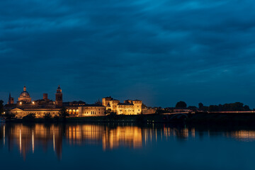 Fototapeta na wymiar Panorama of the city of Mantua illuminated and reflected in the lake water