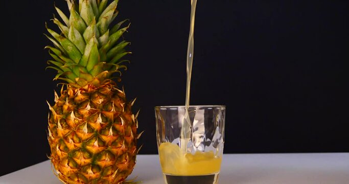 juice is poured into a glass and there is a pineapple fruit nearby