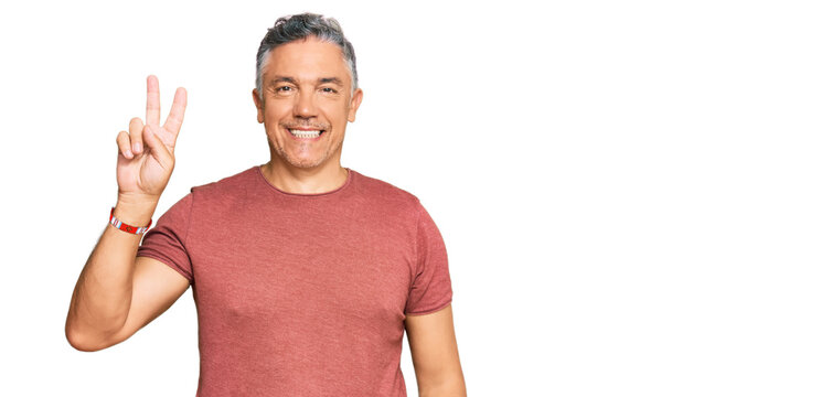 Handsome middle age man wearing casual clothes smiling with happy face winking at the camera doing victory sign. number two.