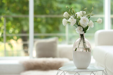 Vase with fresh flowers on white table in living room. Space for text