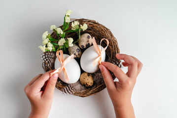 Child holding Easter eggs and flowers in  nest on white background. Greeting card