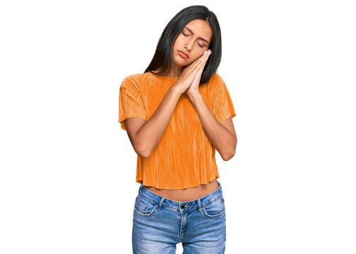 Young brunette arab woman wearing casual clothes sleeping tired dreaming and posing with hands together while smiling with closed eyes.