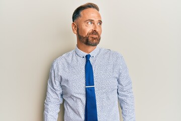 Handsome middle age man wearing business shirt and tie smiling looking to the side and staring away thinking.