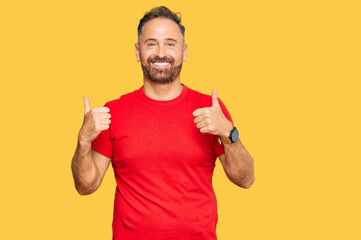 Handsome middle age man wearing casual red tshirt success sign doing positive gesture with hand, thumbs up smiling and happy. cheerful expression and winner gesture.