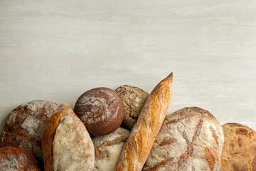 Different kinds of fresh bread on white wooden table, flat lay. Space for text