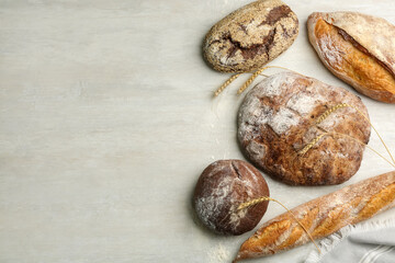 Different kinds of fresh bread on white wooden table, flat lay. Space for text