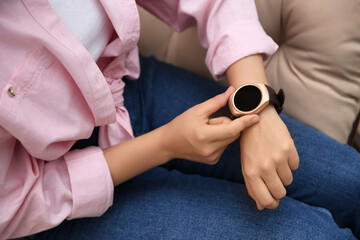 Fototapeta na wymiar Woman using modern smartwatch in armchair, closeup