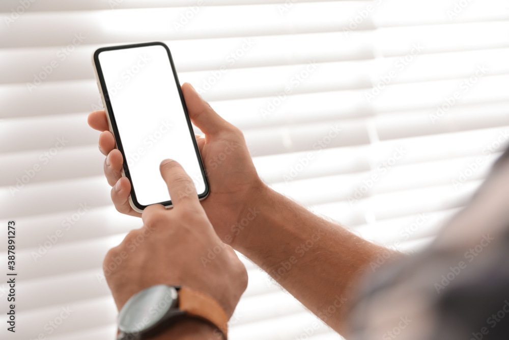 Wall mural man using mobile phone with empty screen near window indoors, closeup