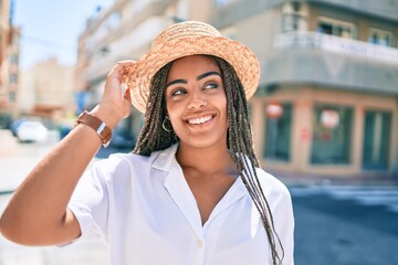 Young african american woman with braids smiling happy outdoors on a sunny day of summer