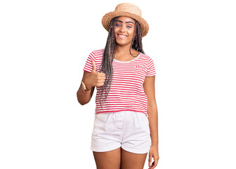 Young african american woman with braids wearing summer hat doing happy thumbs up gesture with hand. approving expression looking at the camera showing success.