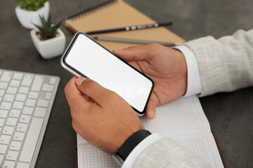 Man holding mobile phone with empty screen at table, closeup