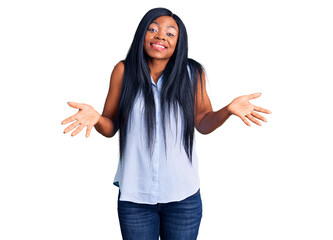 Young african american woman wearing casual clothes clueless and confused expression with arms and...